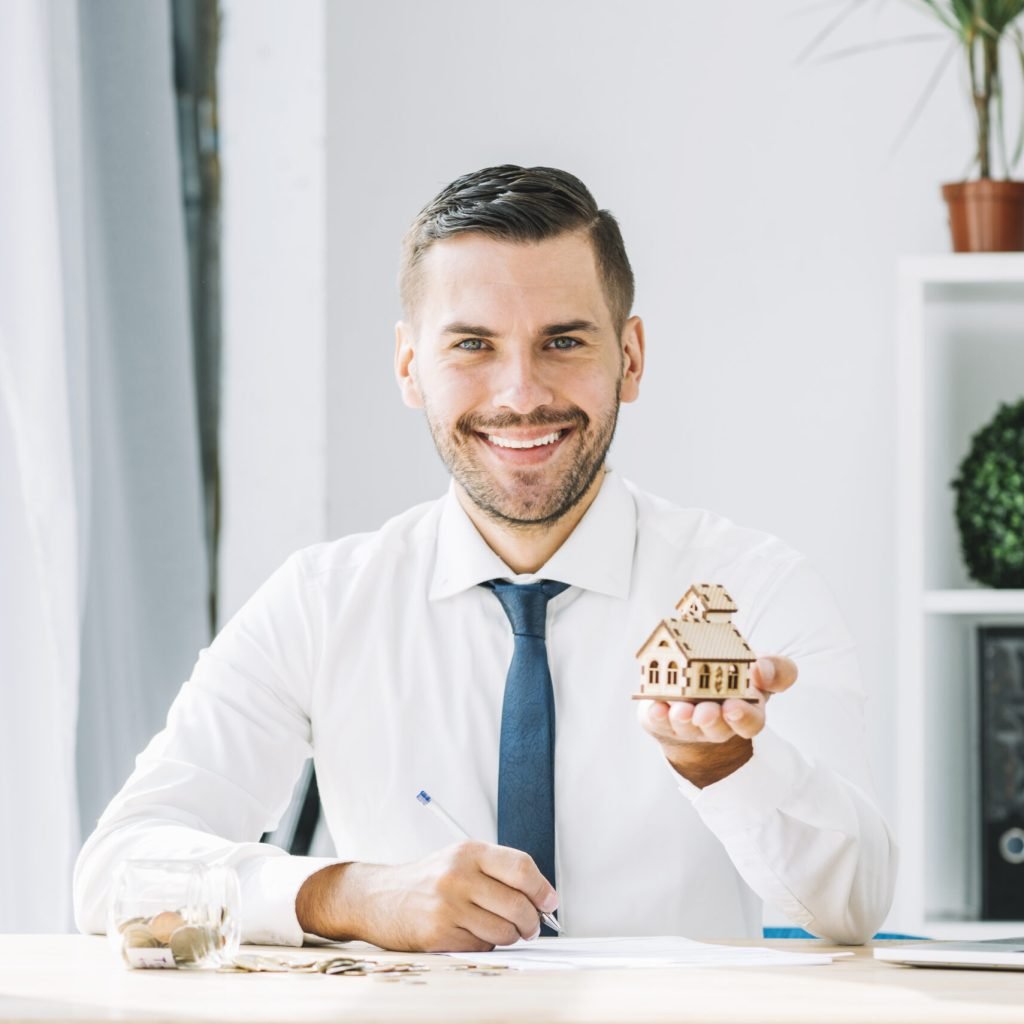 cheerful-real-estate-agent-showing-toy-house