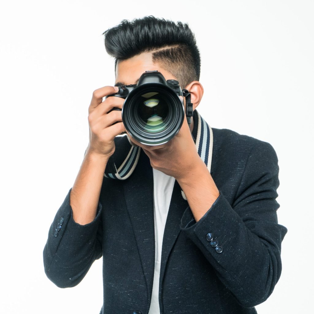Young Asian man with camera isolated on white background.